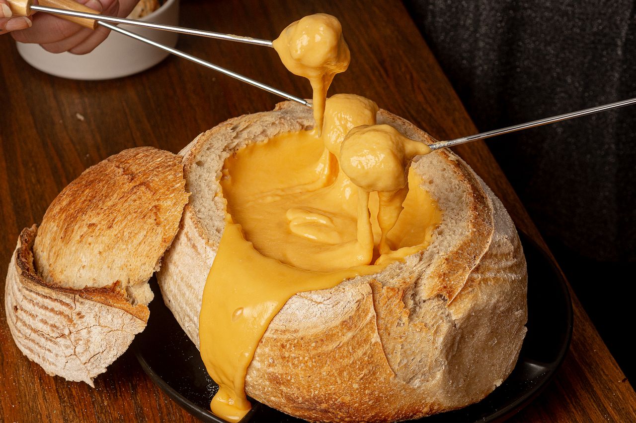 Scrumptious cheese fondue in a rustic bread bowl on a wooden table.
