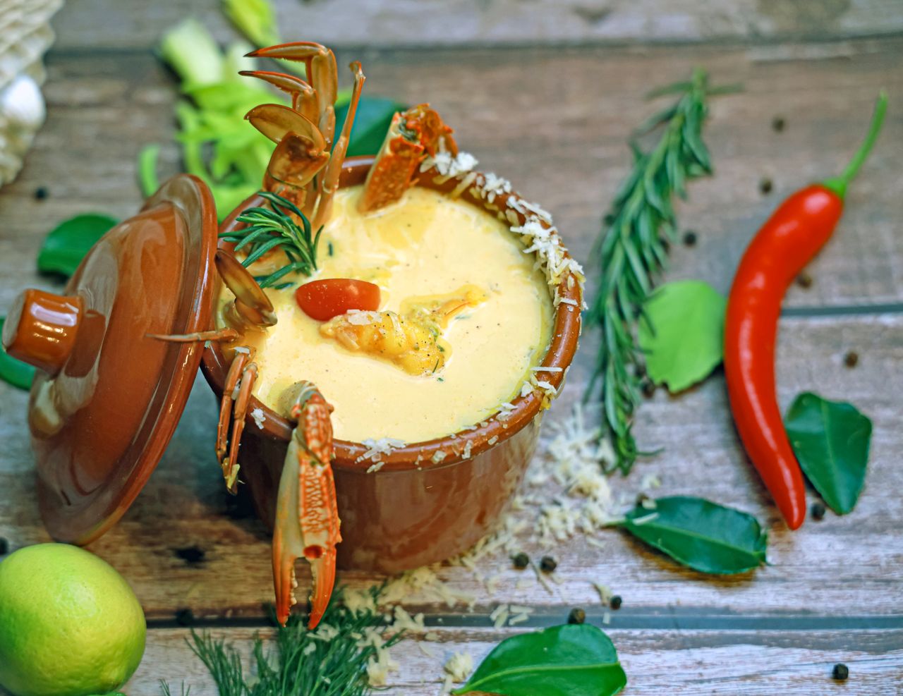 A rich creamy seafood soup garnished with herbs and spices on a rustic wooden table.